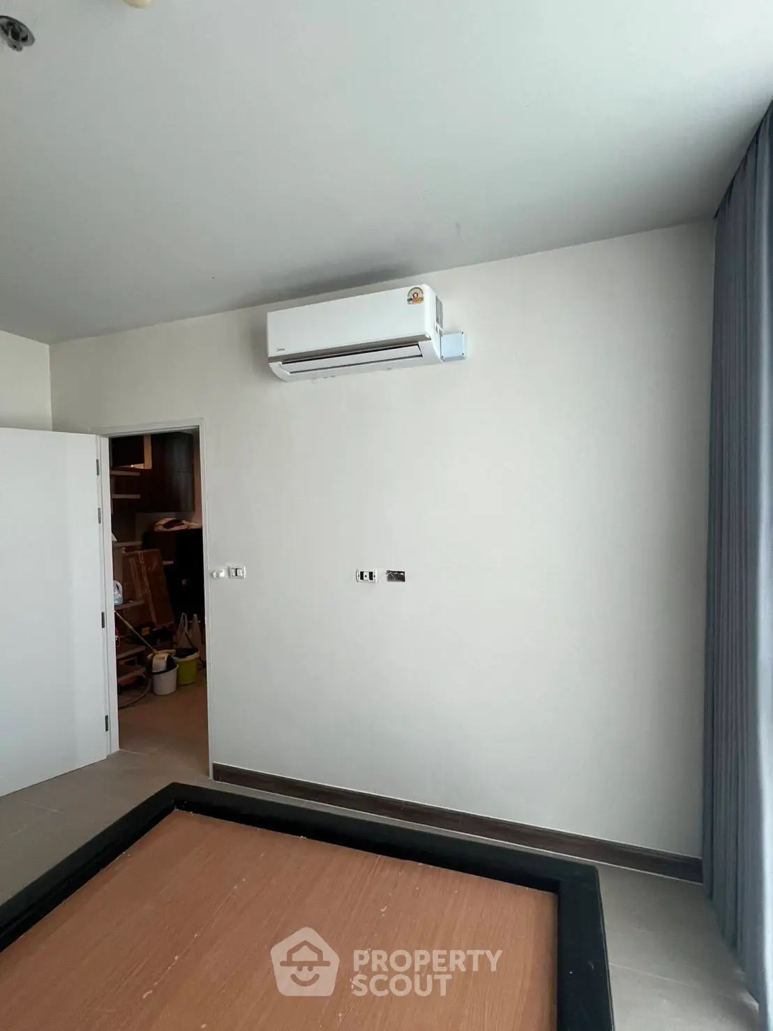 Minimalist bedroom with air conditioning and partially assembled bed frame.