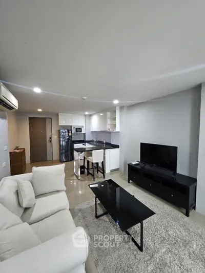 Modern living room with sleek furniture and open kitchen layout in a stylish apartment.
