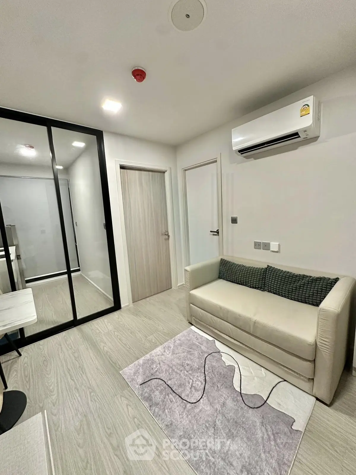 Modern living room with sleek design, featuring a cozy sofa, air conditioning, and stylish decor.