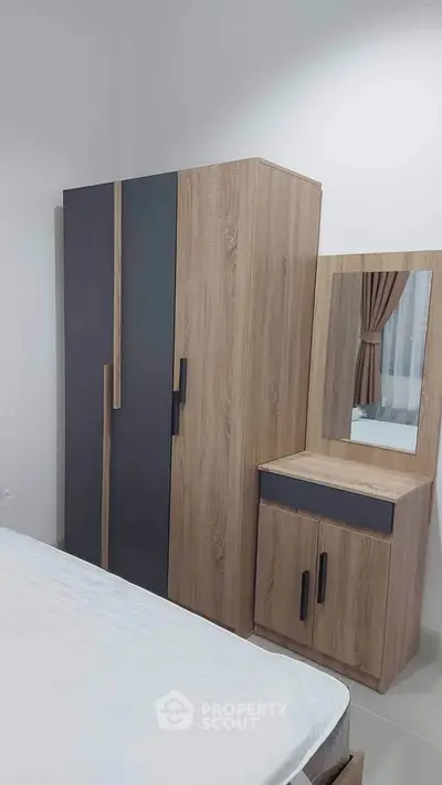 Modern bedroom with sleek wooden wardrobe and dresser, featuring a minimalist design.