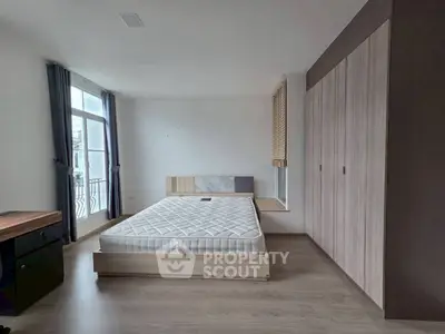 Spacious bedroom with modern design and natural light, featuring a large window and stylish wardrobe.