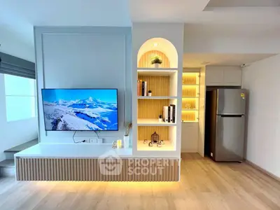 Modern living room with built-in TV unit and stylish shelving, featuring a sleek refrigerator and warm lighting.