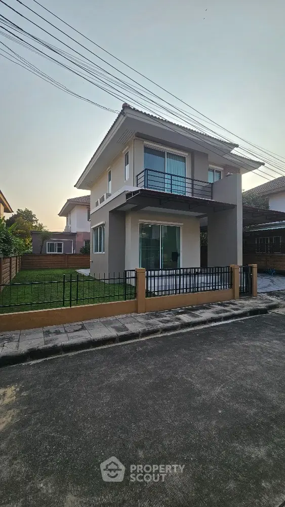 Modern two-story house with balcony and fenced yard in suburban neighborhood