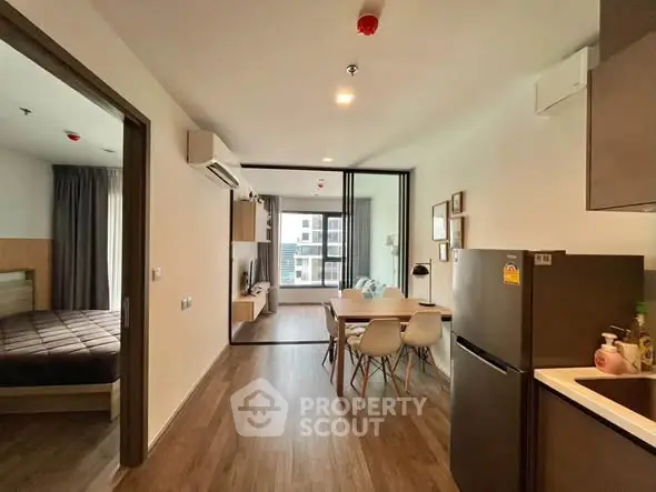 Modern open-plan apartment with stylish kitchen and cozy living area, featuring sleek wooden flooring and ample natural light.