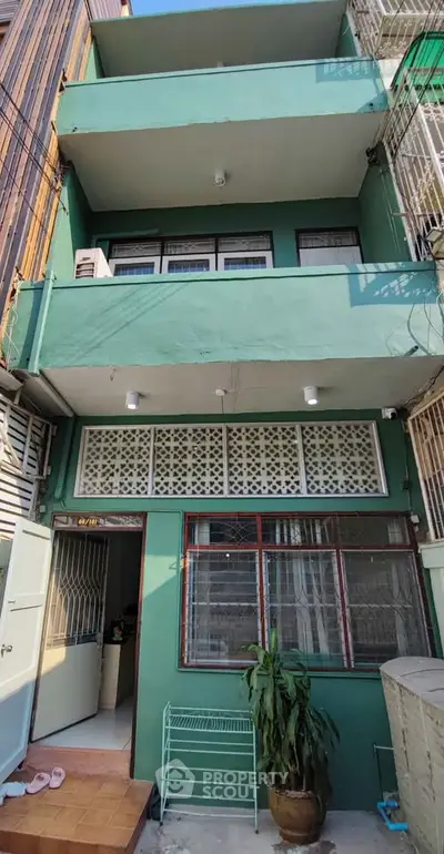 Charming three-story green building with unique facade and open balconies