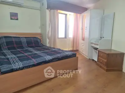 Spacious bedroom with wooden flooring and ample natural light