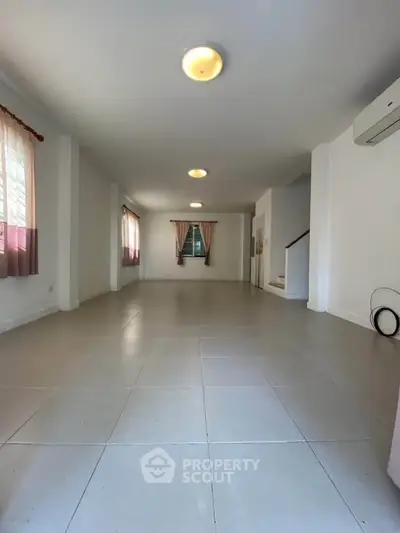 Spacious unfurnished living room with tiled flooring and natural light.