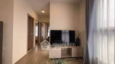 Modern living room with sleek TV stand and natural light from large windows.