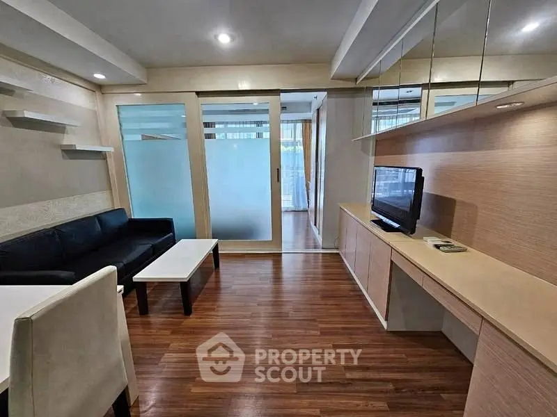 Modern living room with sleek design and wooden flooring, featuring a comfortable sofa and flat-screen TV.