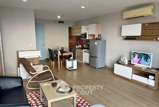 Spacious open-plan living room with modern kitchen and dining area, featuring stylish furniture and wooden flooring.