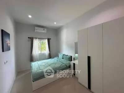 Modern bedroom with minimalist design, featuring a cozy bed and sleek wardrobe.
