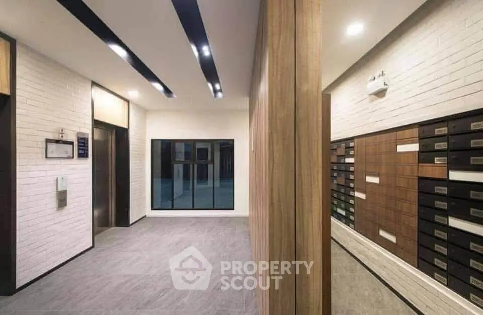 Modern apartment building lobby with sleek elevator and mailboxes.