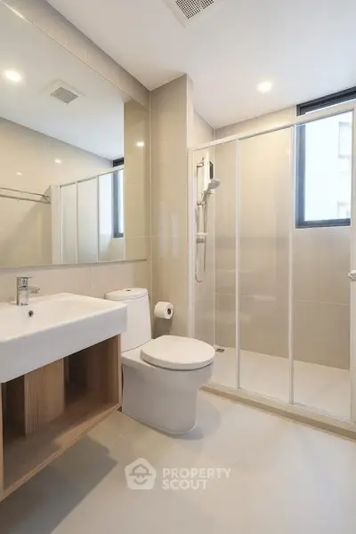 Modern bathroom with sleek design, featuring a glass shower enclosure and contemporary fixtures.