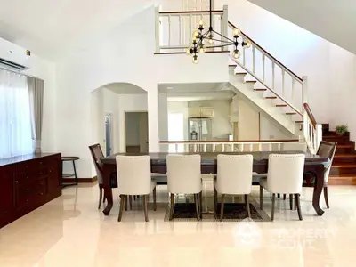 Elegant dining area with modern chandelier and staircase in spacious home