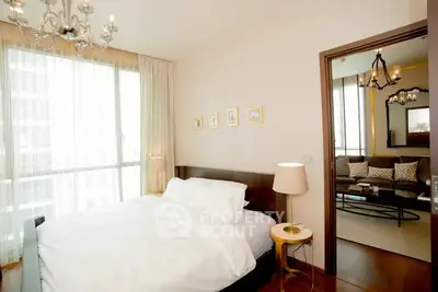 Elegant bedroom with modern decor and natural light, adjacent to a stylish living room.