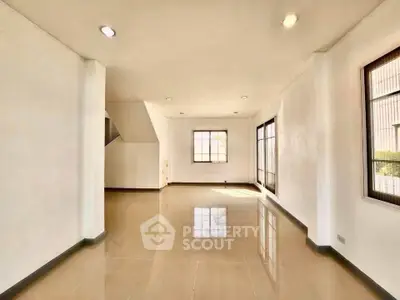 Spacious and bright living room with large windows and glossy tiled floors
