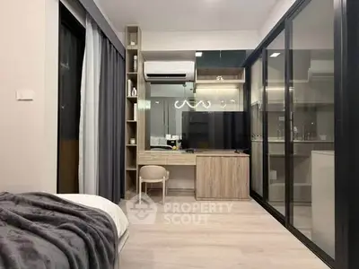 Modern bedroom with sleek design and glass partition, featuring a cozy workspace and air conditioning.