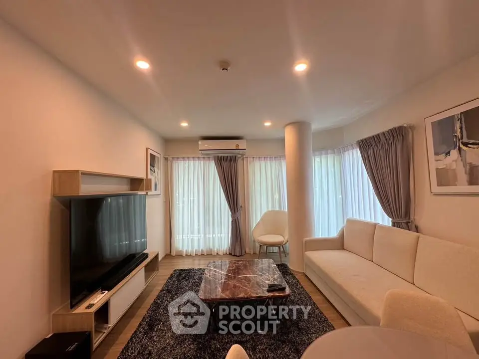 Modern living room with elegant decor, featuring a large TV, stylish sofa, and ambient lighting.