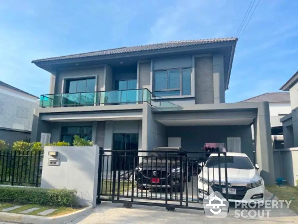 Modern two-story house with spacious balcony and gated driveway