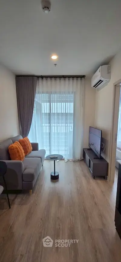 Modern living room with cozy sofa, TV, and balcony view in stylish apartment.
