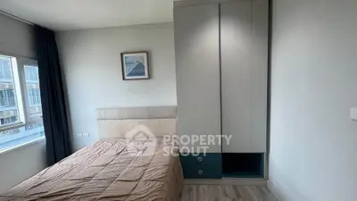 Cozy bedroom with modern wardrobe and large window offering natural light.