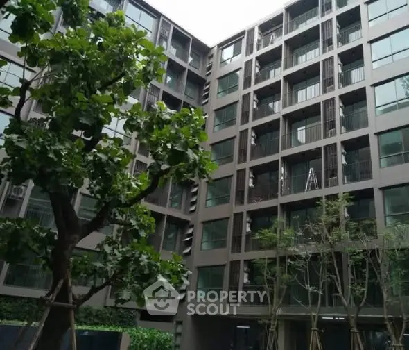 Modern apartment building exterior with lush greenery and large windows