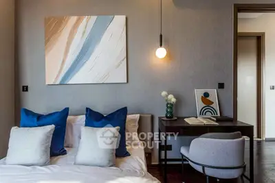 Modern bedroom with stylish decor and cozy workspace, featuring elegant lighting and contemporary artwork.