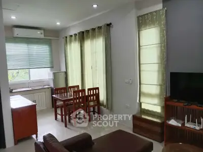 Spacious living room with dining area and natural light, featuring modern furniture and air conditioning.