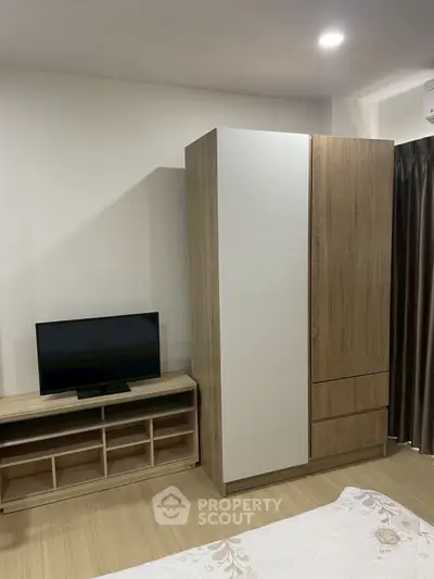 Modern bedroom with sleek wardrobe and TV stand, perfect for urban living.