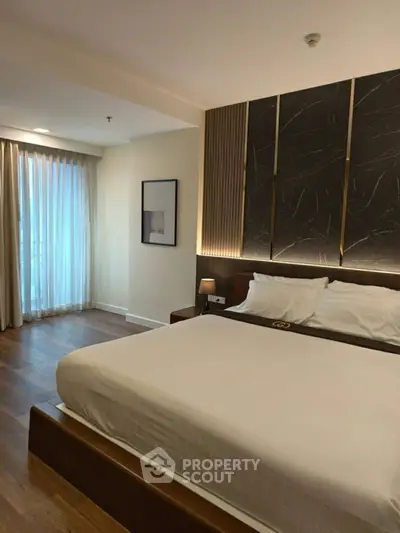 Luxurious modern bedroom with elegant decor and large window for natural light.