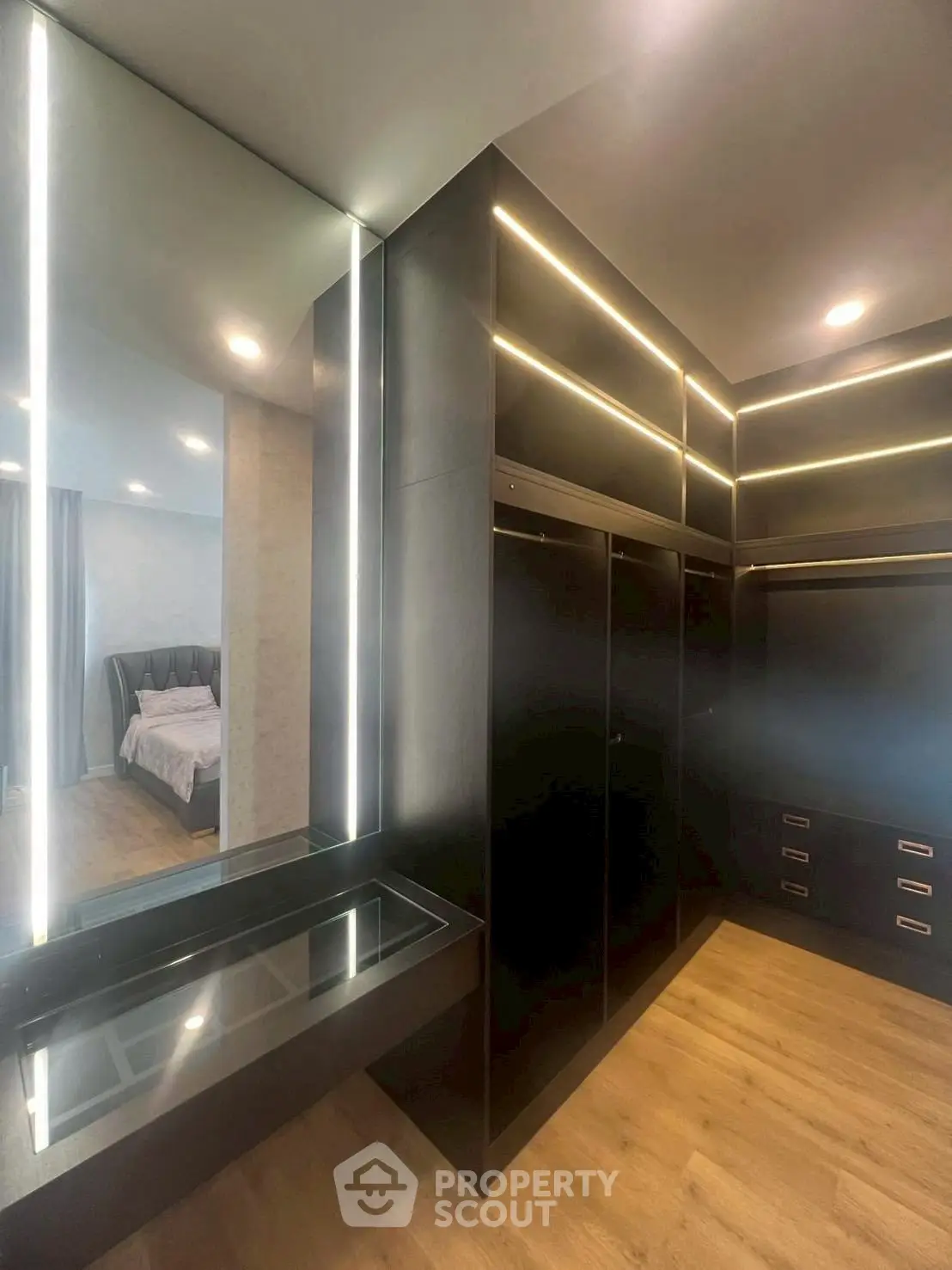 Luxurious walk-in closet with sleek black cabinetry and ambient lighting