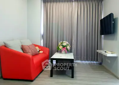 Modern living room with vibrant red sofa and wall-mounted TV, perfect for cozy relaxation.