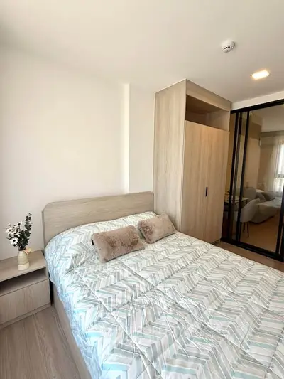Modern bedroom with stylish decor and ample natural light, featuring a cozy bed and sleek wardrobe.