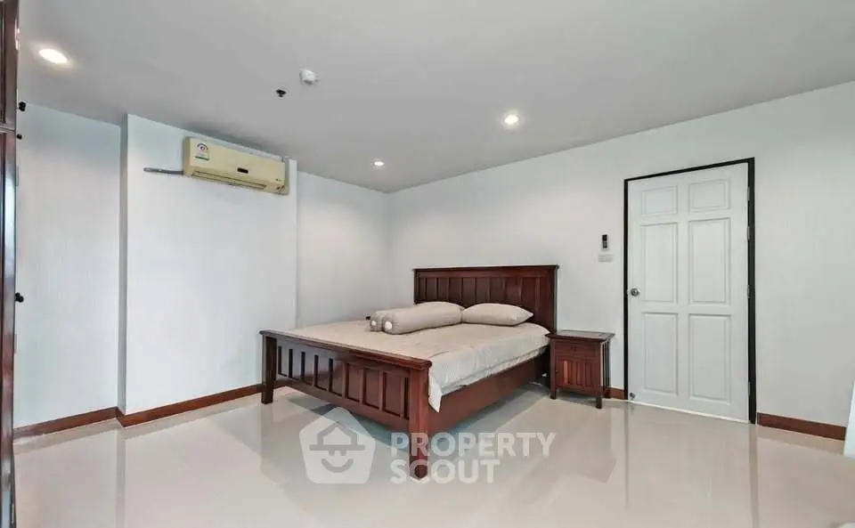 Spacious bedroom with elegant wooden bed and modern air conditioning unit.