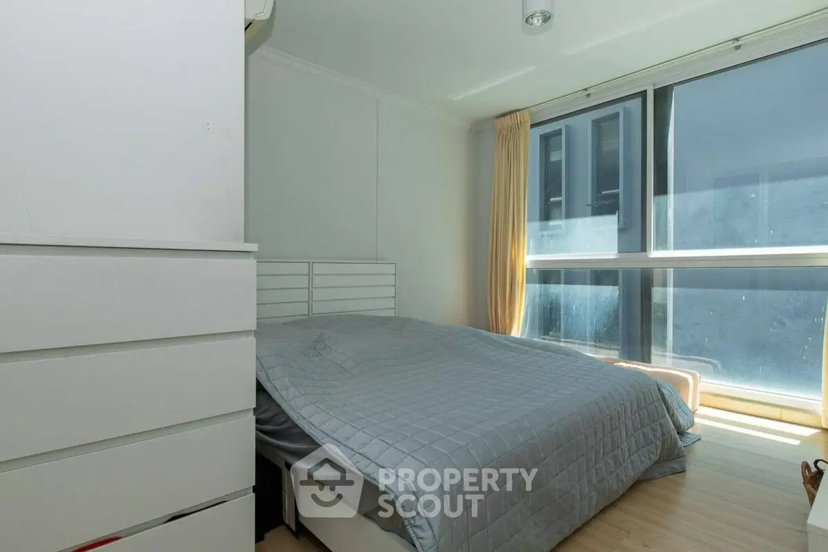 Bright and cozy bedroom with large window and modern furnishings.