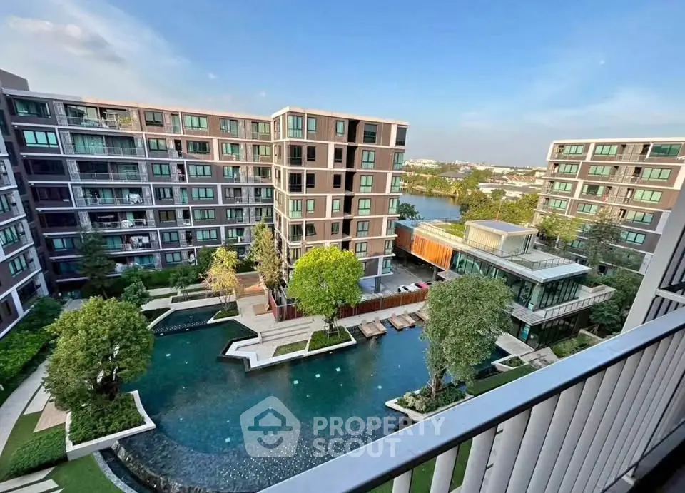 Stunning view of modern apartment complex with pool and lush greenery, perfect for urban living.