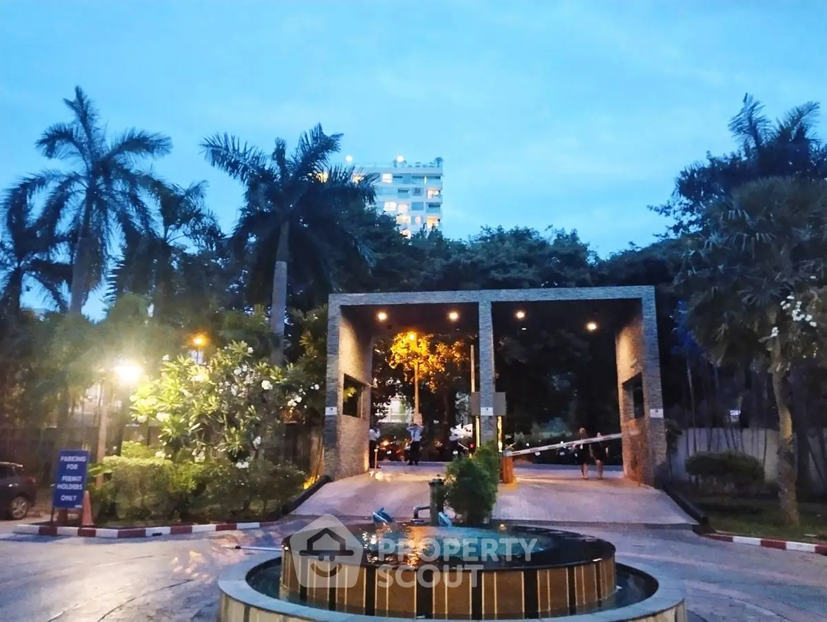 Luxurious entrance with fountain and palm trees at dusk, showcasing elegance and exclusivity.