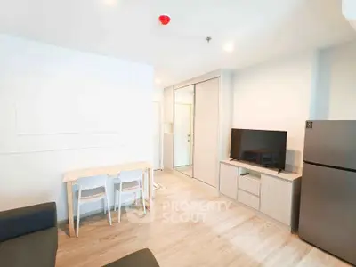 Modern living room with sleek furniture and natural light, featuring a TV and dining area.