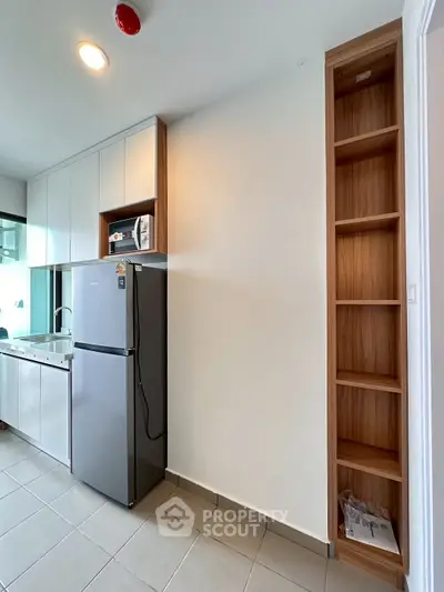 Modern kitchen with sleek cabinetry and stainless steel fridge in a compact apartment.