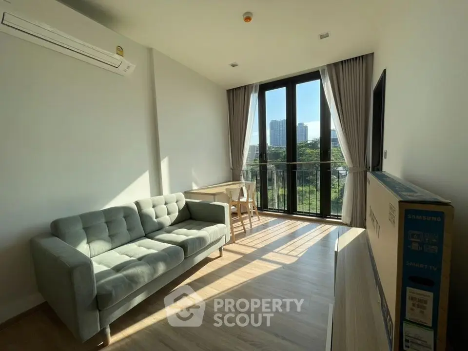 Modern living room with large windows and city view, featuring a stylish sofa and natural light.
