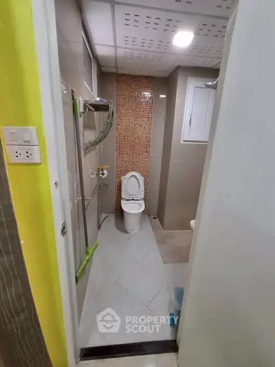 Compact bathroom with modern fixtures and tiled walls in a cozy apartment.