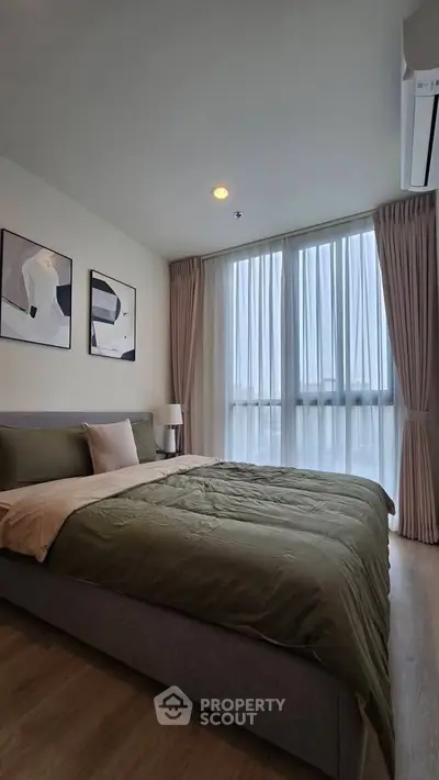 Modern bedroom with large windows and stylish decor in a contemporary apartment.