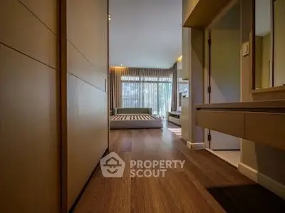 Luxurious bedroom with wooden flooring and large windows offering natural light.