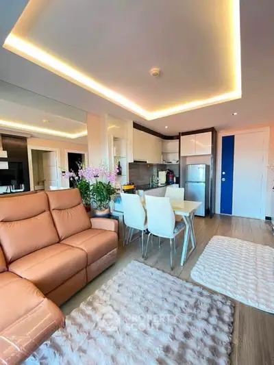 Modern living room with open kitchen, stylish lighting, and cozy seating area.