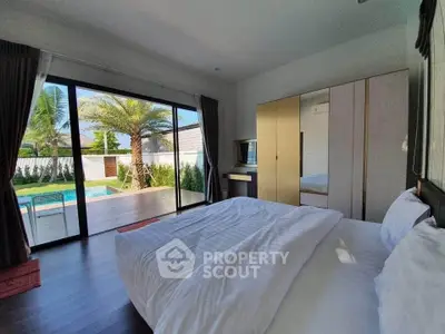 Luxurious bedroom with pool view and modern furnishings in a tropical setting.