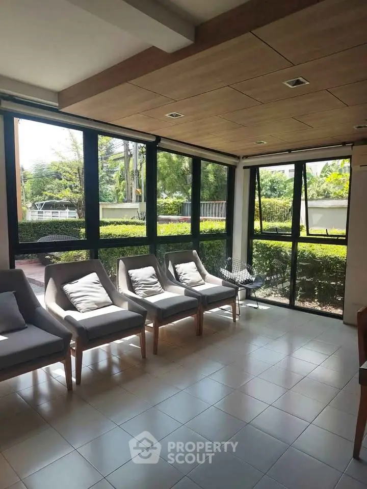 Bright and airy living room with large windows and garden view, featuring modern seating and stylish decor.