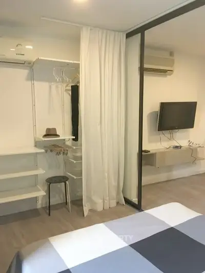 Modern bedroom with open closet and wall-mounted TV in stylish apartment.