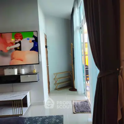 Modern living room with large TV, stylish decor, and balcony access.