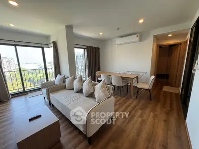Spacious modern living room with large windows and stylish furniture in a high-rise apartment.