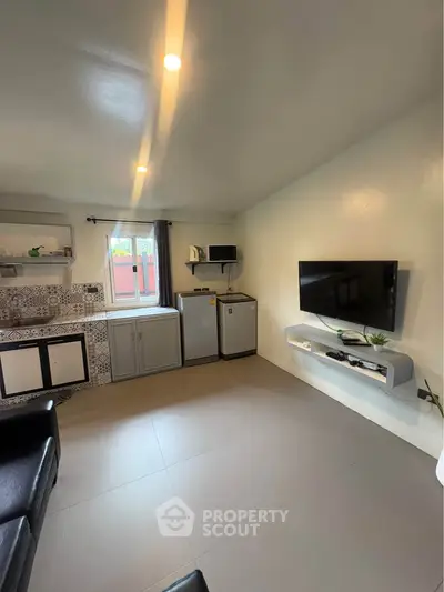 Modern living room with wall-mounted TV and compact kitchen area